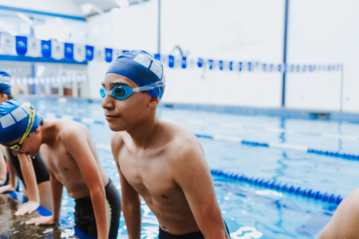 latin young man swimmer wearing cap and goggles in a swimming training session